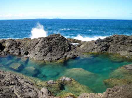 Low tide waves crash against the rocks which cradle the Mermaid Pool.